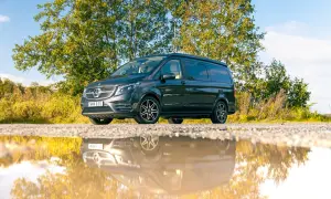 Mörkgrå Mercedes-Benz Vito med takhöjning, perfekt för service och äventyr. Reflekteras i en vattenpöl.