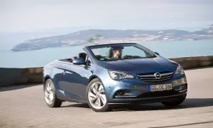 En blå Opel Cascada cabriolet kör längs en kustväg med havet i bakgrunden.