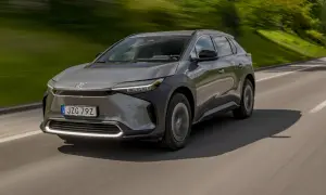 Grå Toyota bZ4X kör på en väg, med grönskande natur i bakgrunden. Ett potentiellt toyota bz4x problem kan vara dess räckvidd.
