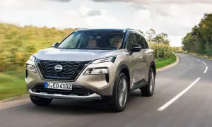 En man kör en beige Nissan X-Trail på en kurvig landsväg. Inga problem syns med bilen.