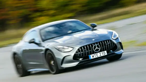 Grå Mercedes AMG GT accelererar på en väg. Lär dig hur startar man en manuell bil och njut av körglädjen.