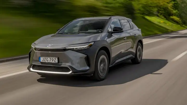 Grå Toyota bZ4X kör på en väg, med grönskande natur i bakgrunden. Ett potentiellt toyota bz4x problem kan vara dess räckvidd.